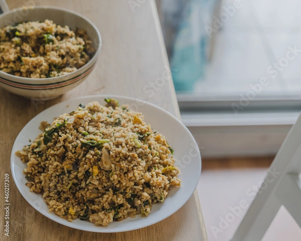 Obraz Stir fried rice with chicken ,kale ,onion, egg in a white plate on the wood table for cooking.