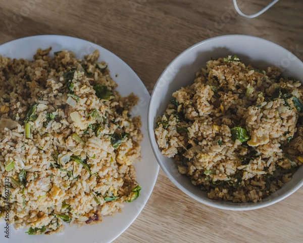 Obraz Stir fried rice with chicken ,kale ,onion, egg in a white plate on the wood table for cooking.