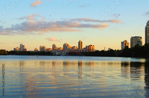 Fototapeta Amazing autumn landscape during sunset. Buildings reflected in the tranquil water of the Dnieper River. High rise buildings of the Obolon neighborhood in the background