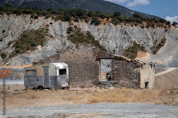 Fototapeta An old caravan parked in front of a dilapidated house.