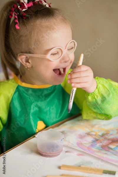 Fototapeta Girl with Down syndrome covered in paint when drawing