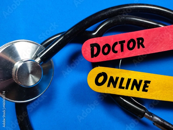 Fototapeta Colored ice cream sticks written with text DOCTOR ONLINE with stethoscope on a blue background.