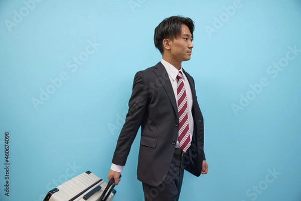 Fototapeta キャリーケースを持って歩く日本人男性ビジネスマン