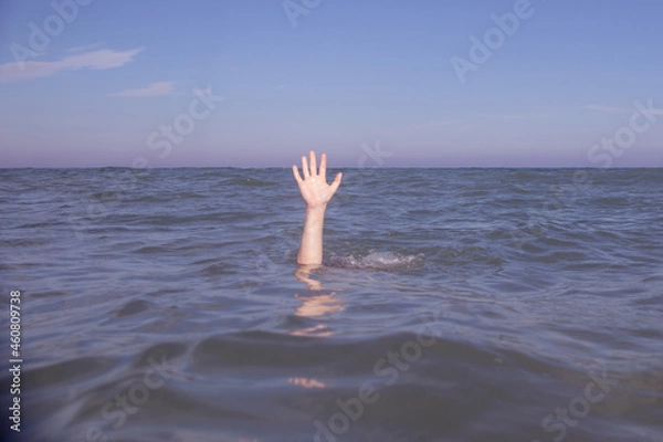 Obraz Person submerged on a beach with hand out pretending to be drowning