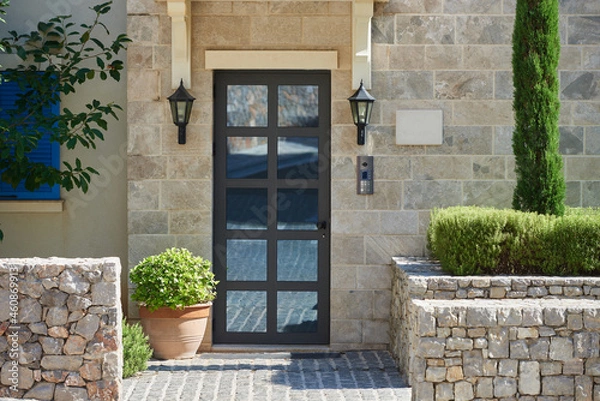 Obraz Modern house facade with stone finished wall, glass door and bushes in europe