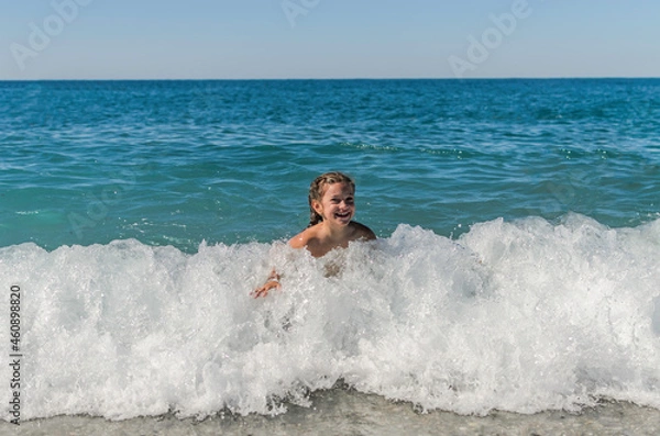 Obraz Little happy adorable girl child swims in the sea and plays on the waves during the holidays on the sea coast