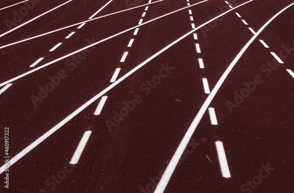 Fototapeta All-weather running track, white dash and solid lines crosses on brown rubber racetracks, selective focus. Racing curve on runner lanes surface, depth of field. Competition, pace abstract concept.