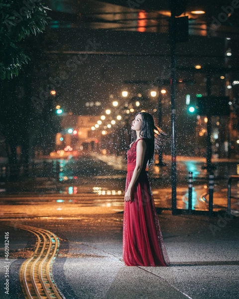 Obraz 雨の街に立つ赤いドレスの女性