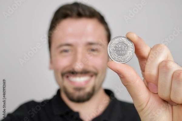 Fototapeta Young caucasian man showing two Swiss francs coin  