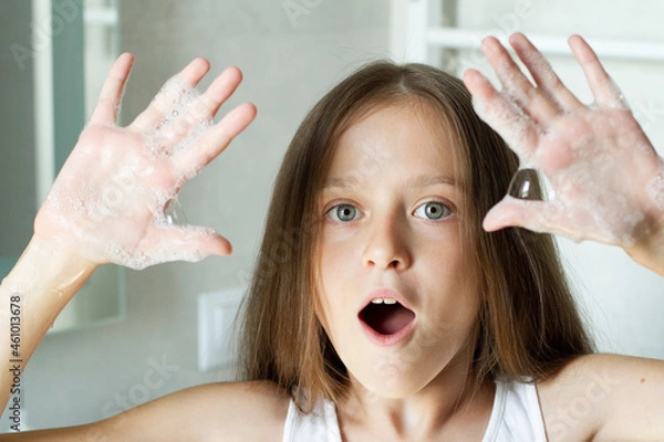 Fototapeta Happy smiling girl having fun with soap bubble in lockdow. COVID-19 Coronavirus prevention washing hands with soap at bathroom.