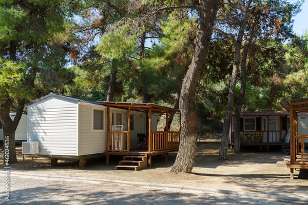 Fototapeta Vacation mobile houses on a campsite with trees around. High quality photo