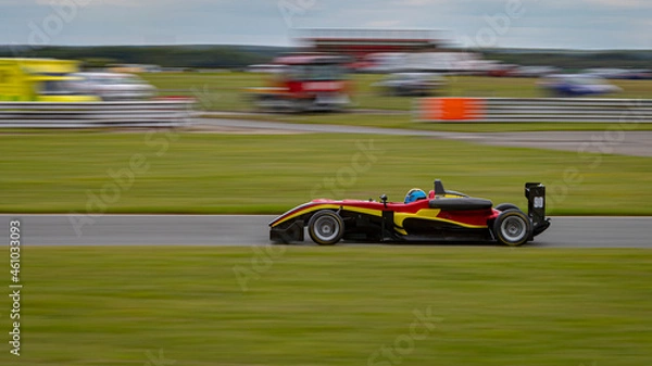 Fototapeta A panning shot of a racing car as it circuits a track.