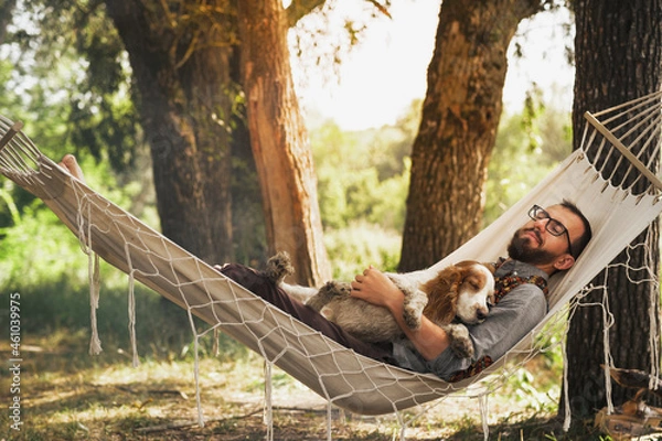 Fototapeta Person sleeping with his dog in a hammock in beautiful summer scene