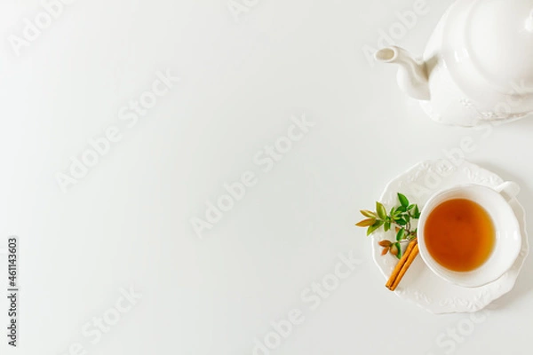 Fototapeta Cup of tea frame with tea pot and green leaves on white background. Flat lay, top view. 