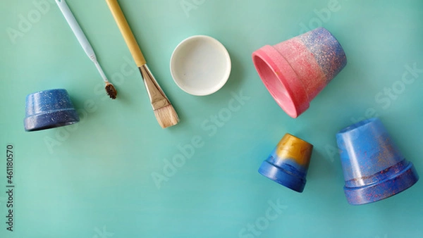 Obraz Flat lay of colorful painted terracotta pots, paintbrush, toothbrush and a paint tray. With copy space on the bottom left corner.