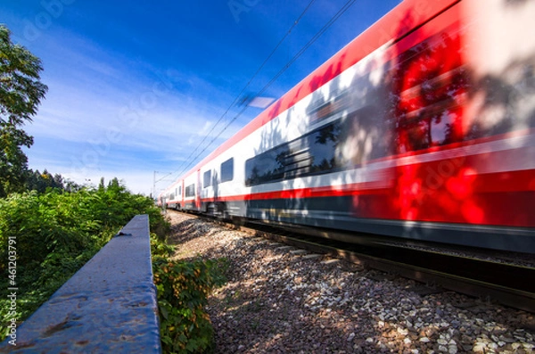 Fototapeta A speeding train on railroad tracks, image blurred by speed. Vivid picture.