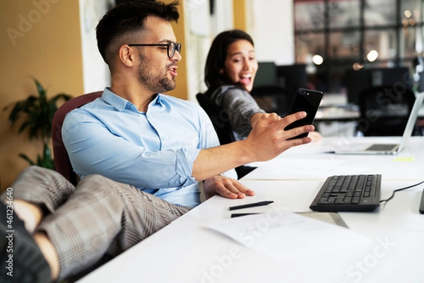 Fototapeta Colleagues in office. Businesswoman and businessman discussing work in office. Two friends working together.