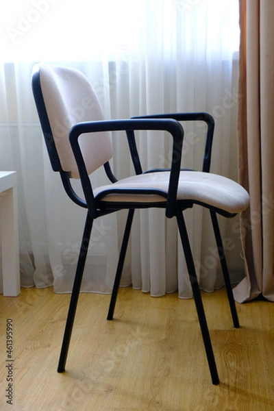 Fototapeta Stylish modern chair with a soft back and seat against a neutral beige room background. Simplicity and comfort.
