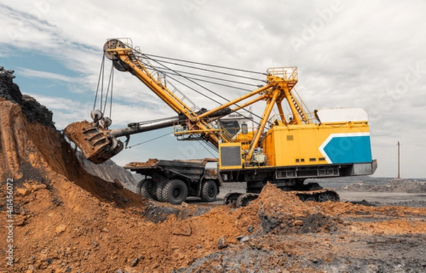 Obraz Large quarry dump truck. Big yellow mining truck at work site. Loading coal into body truck. Production useful minerals. Mining truck mining machinery to transport coal from open-pit production