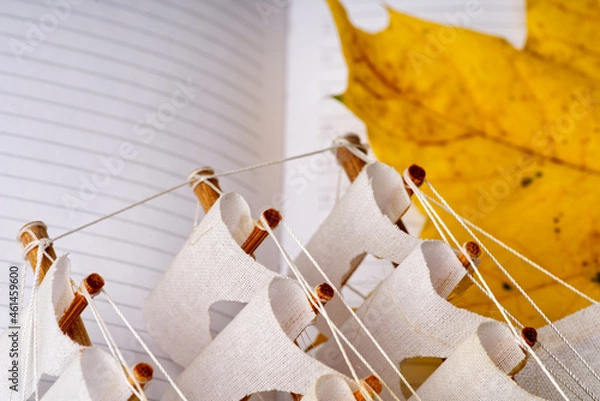 Fototapeta A yellow autumn leaf lies next to the pages of the diary and a small model ship.