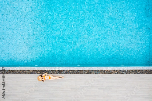 Fototapeta Top view of slim young woman in hat relaxing in resort swimming pool. Female enjoying sunbathing.