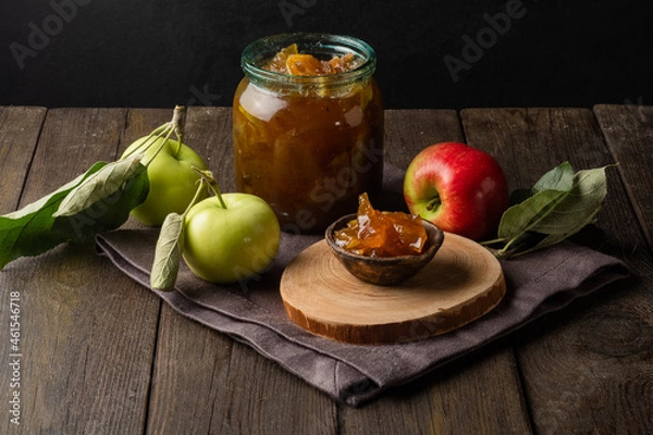 Obraz Tasty homemade apple jam, confiture in a glass jar with apples on a black wooden table