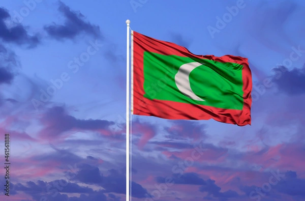 Fototapeta National flag of Maldives on a flagpole in front of blue sky