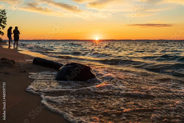 Fototapeta People watching sunset along beach on Lake Michigan.  