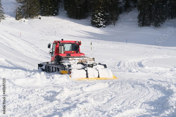 Fototapeta red tractor of municipal service in mountains of Swiss Alps with wide snow shovel clears the road from heavy snow, Winter Activity Concept, travel by car, problems of utilities in winter
