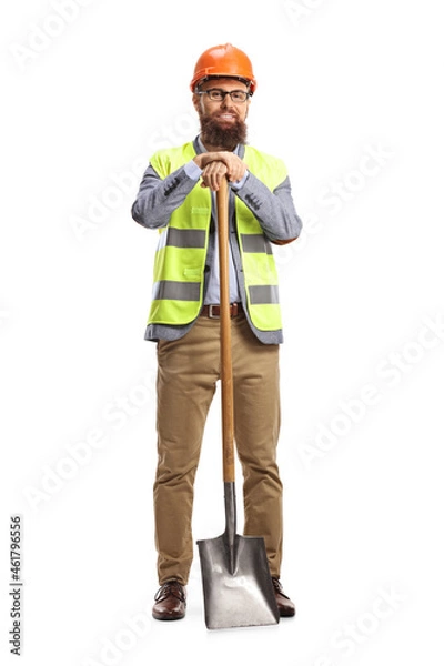 Fototapeta Site engineer with a vest and a helmet leaning on a shovel