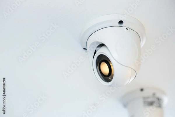 Fototapeta CCTV security camera on white ceiling, operating inside the building with copy space. concept of safety control, crime protect.
