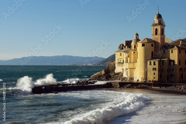 Obraz Stunning view of the picturesque town of Camogli with its church on the sea and the waves crashing on the dock.
