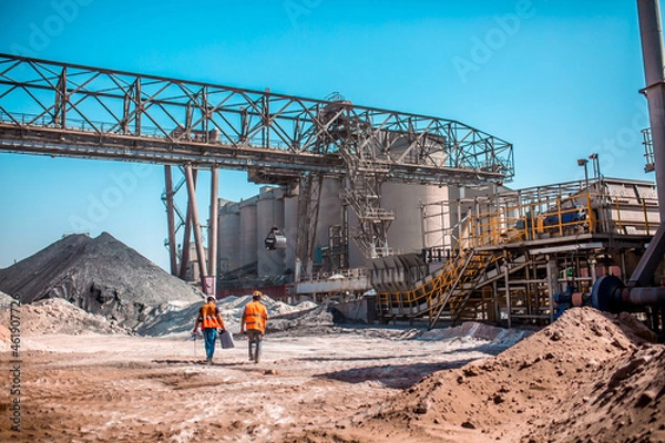 Obraz People are working in the industry. Modern technologies work at a cement plant. Technological work on the production of cement. Working atmosphere with copy space. Heaps of sand and soil raw materials