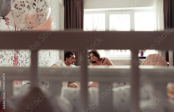 Obraz Lifestyle soot of loving family with newborn twins. A view through the baby-cot bars. Selective focus. Film grain