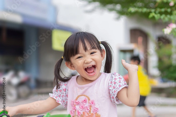Fototapeta Portrait​ image of​ 3-4 years old​ childhood​ child. Face of smile and laugh Asian​ girl in head shot. Happy​ kid playing​ at the park playground. In summer or spring​ season.