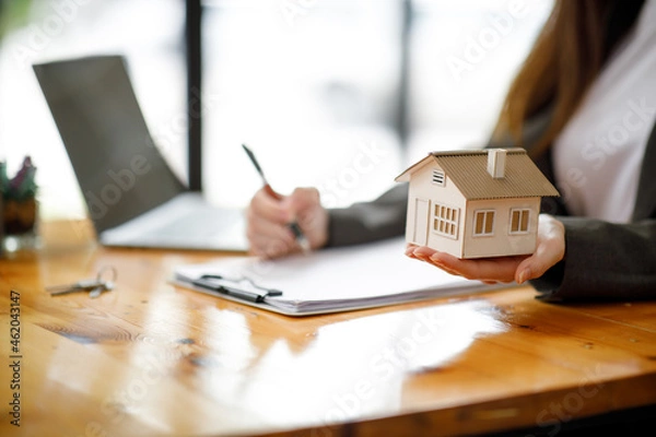 Fototapeta Real estate broker agent presenting and consult to the customer to decision making sign insurance form agreement, buy and sell home model, concerning mortgage loan offer for and house insurance