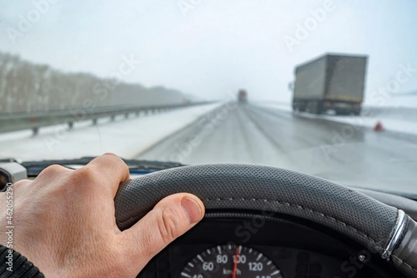 Fototapeta view of a car driver hand on the steering wheel during dangerous driving on a slippery road
