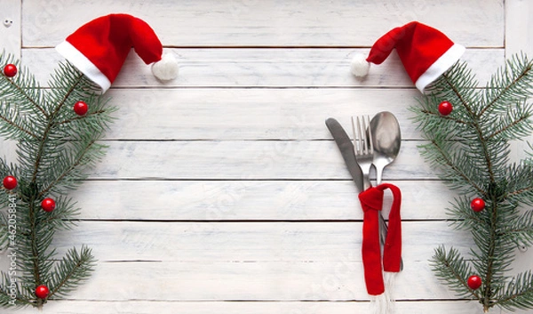 Obraz spruce branches in red caps and cutlery tied with a red scarf on a white wooden background. Christmas concept