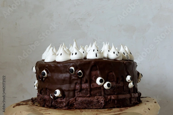 Obraz Halloween themed chocolate cake with chocolate cream, chocolate glazing and white meringue ghosts and googly eyes
