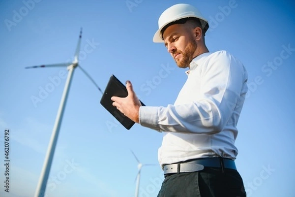 Fototapeta Young engineer man looking and checking wind turbines at field