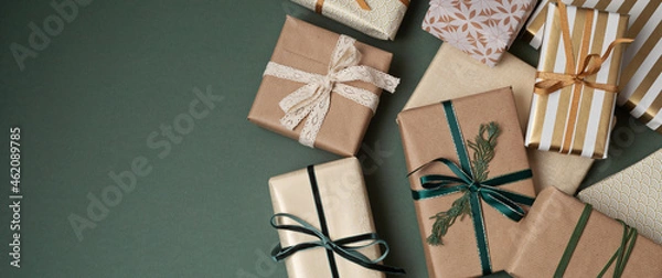 Obraz Christmas background with gift boxes over green backdrop. Xmas celebration, preparation for winter holidays, secret Santa, advent calendar concept. Festive banner, website header, top view, flat lay