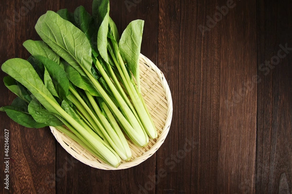 Obraz 木製テーブルにあるザルの中の複数の小松菜