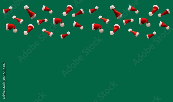 Fototapeta red Christmas hats on a green background, creative concept of Christmas with free space for text