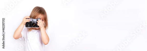 Obraz A cute child takes pictures with a retro camera.