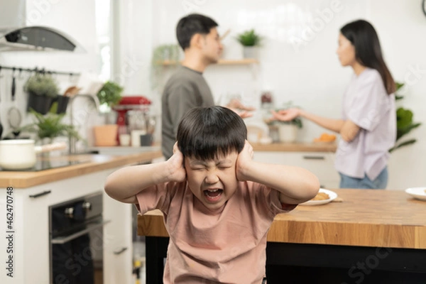 Fototapeta Little asian sad boy, unhappy while parents fighting, kid son not listen to shouting noise while mom and dad arguing, quarrel behind. Family suffering, stressed. Violence and divorce couple concept.