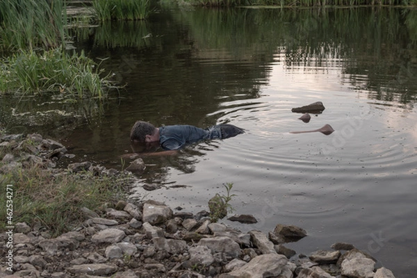 Fototapeta the body of a man who drowned lies face down in the water, the lifeless body of a murdered young man on the river