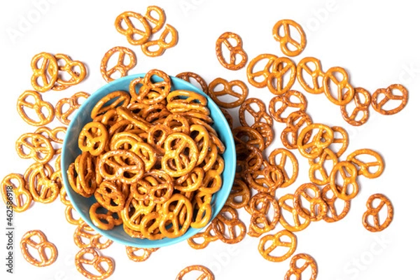 Fototapeta Salted pretzels are in a blue cup. They are also scattered around the cup. Isolated on white background. Top view.