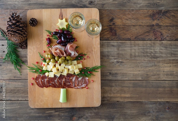 Fototapeta Christmas tree shaped cheese and charcuterie board with wooden background. Top view. Copy space.