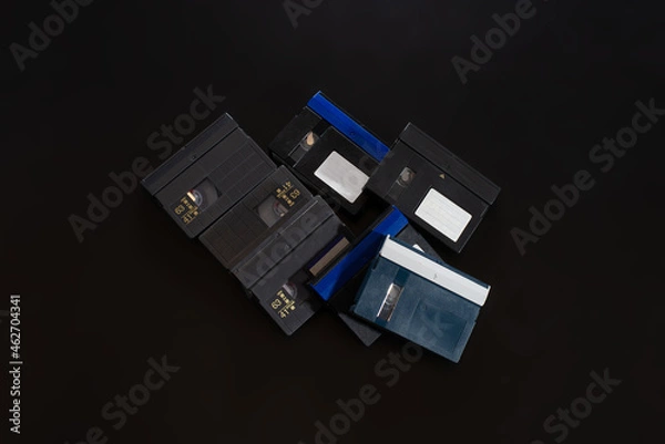 Fototapeta A pile of VHS-c cassettes on a black background. Retro video technology.