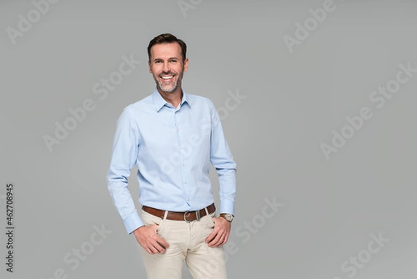 Obraz Photo of a smiling formal business man wearing a light blue shirt,  standing and looking at camera